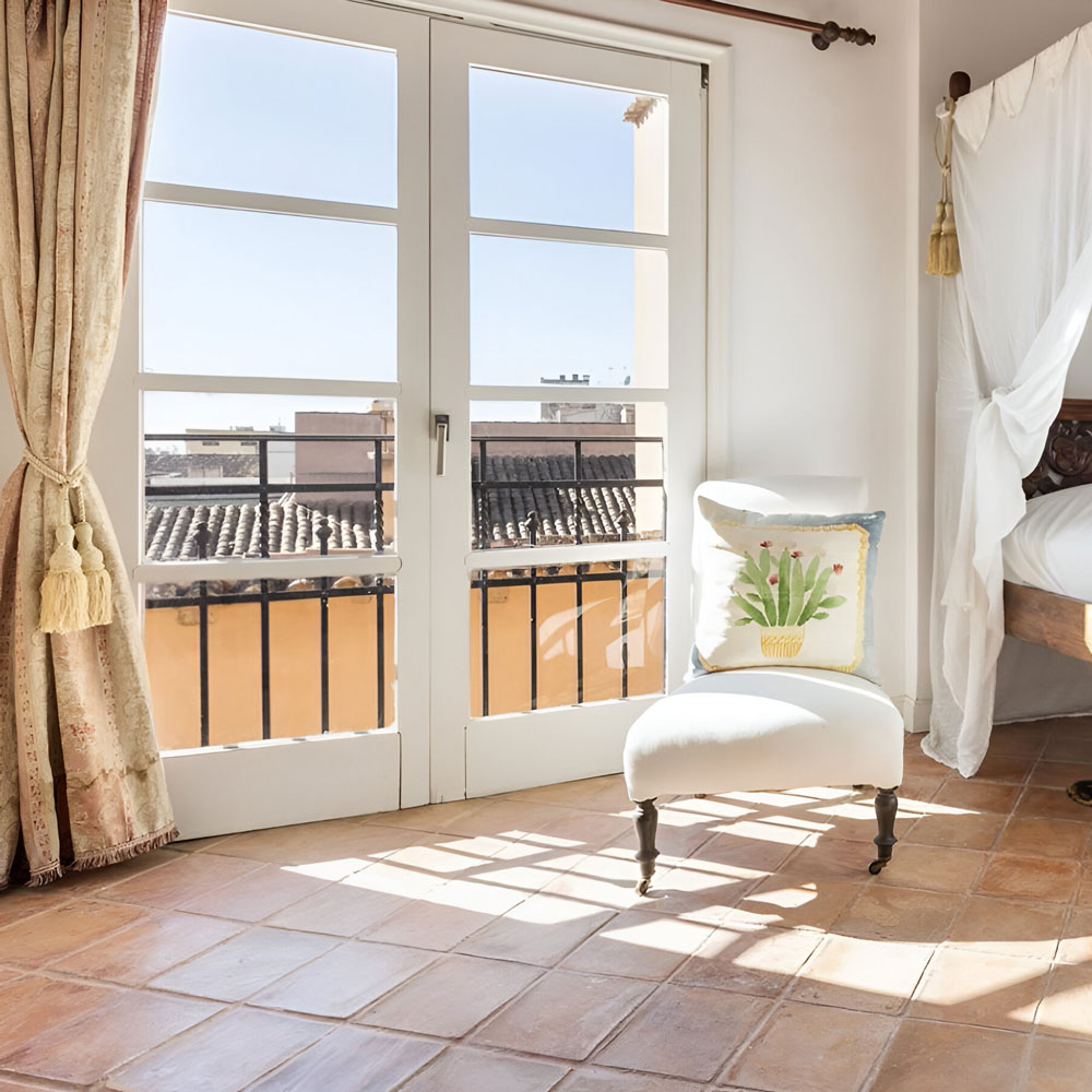Luxus-Penthouse Mallorca mit Terrakottaboden und Altstadtblick durch französische Fenster.